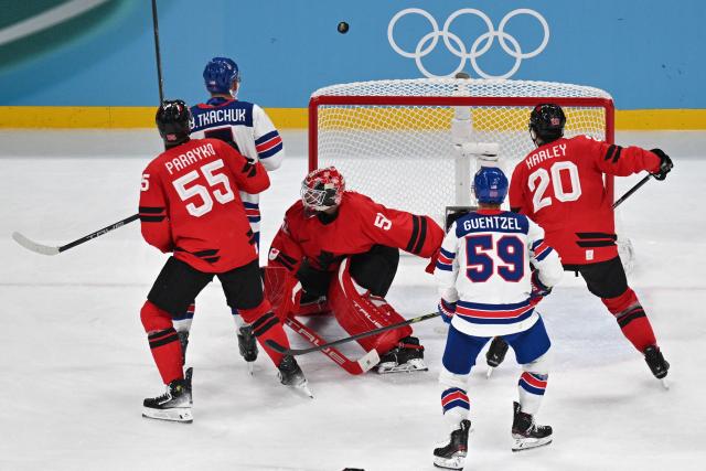 The puck passes over the net as players vie during the men's gold medal ice hockey match between Canada and USA at the Milano Santagiulia Ice Hockey Arena during the Milano Cortina 2026 Winter Olympic Games in Milan, on February 22, 2026. (Photo by Antonin THUILLIER / AFP)