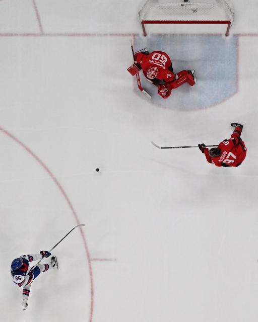 USA's #86 Jack Hughes (bottom L) scores the 1-2 goal in overtime against Canada's #29 Nathan MacKinnon during the men's gold medal ice hockey match between Canada and USA at the Milano Santagiulia Ice Hockey Arena during the Milano Cortina 2026 Winter Olympic Games in Milan, on February 22, 2026. (Photo by JULIEN DE ROSA / AFP)