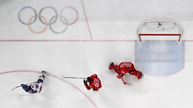 USA's #86 Jack Hughes (L) celebrates after scoring the 1-2 goal in overtime against Canada's #50 Jordan Binnington during the men's gold medal ice hockey match between Canada and USA at the Milano Santagiulia Ice Hockey Arena during the Milano Cortina 2026 Winter Olympic Games in Milan, on February 22, 2026. (Photo by JULIEN DE ROSA / AFP)
