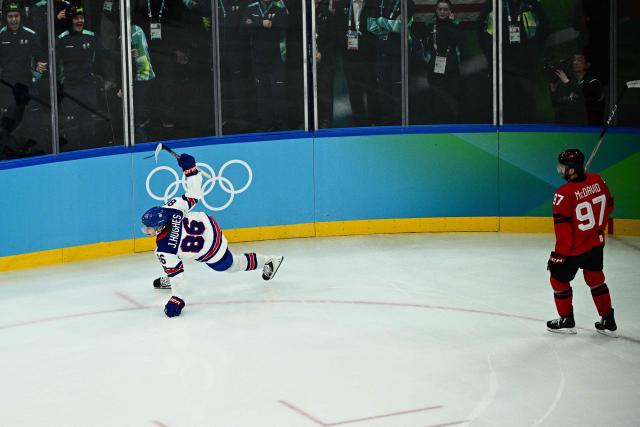 USA's #86 Jack Hughes (L) celebrates after scoring the winning goal  during the men's gold medal ice hockey match between Canada and USA at the Milano Santagiulia Ice Hockey Arena during the Milano Cortina 2026 Winter Olympic Games in Milan, on February 22, 2026. (Photo by JULIEN DE ROSA / AFP)
