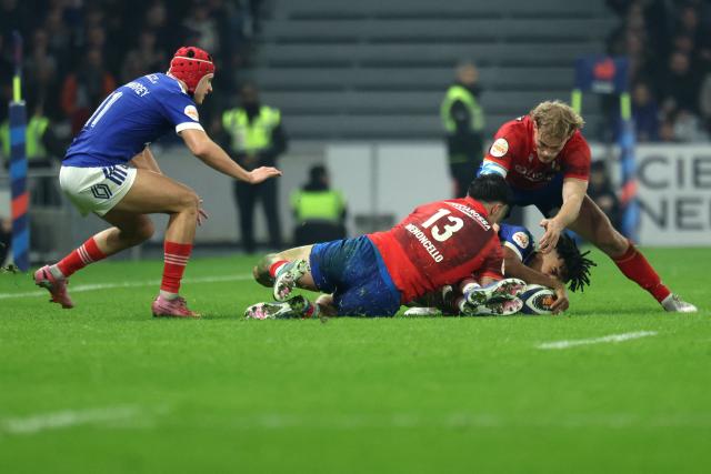 France's wing Théo Attissogbe is tackled by Italy's centre Tommaso Menoncello (C) and Italy's wing Louis Lynagh (R) during the Six Nations international rugby union match between France and Italy at the Stade Pierre-Mauroy in Villeneuve-d'Ascq, northern France, on February 22, 2026. (Photo by Francois LO PRESTI / AFP)
