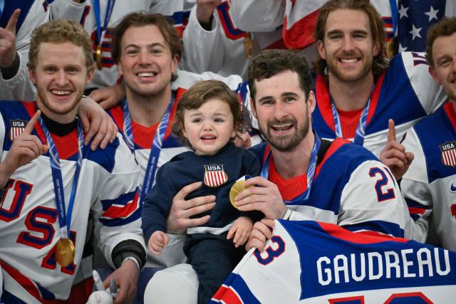 USA's gold medalist #21 Dylan Larkin (C) holds his son amongst teammates as they celebrate with their medals during the medals ceremony of the men's ice hockey event at the Milano Santagiulia Ice Hockey Arena during the Milano Cortina 2026 Winter Olympic Games in Milan, on February 22, 2026. (Photo by Alexander NEMENOV / AFP)