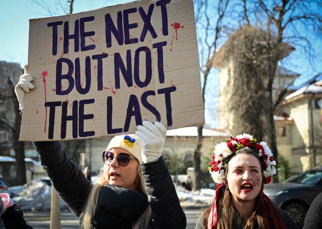 Members of Ukrainian comunity in Romania hold placards during a commemoration of the four years since Russia's invasion of Ukraine in Bucharest, Romania, on February 22, 2026. (Photo by Daniel MIHAILESCU / AFP)