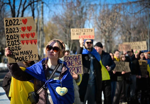 Members of Ukrainian comunity in Romania hold placards during a commemoration of the four years since Russia's invasion of Ukraine in Bucharest, Romania, on February 22, 2026. (Photo by Daniel MIHAILESCU / AFP)