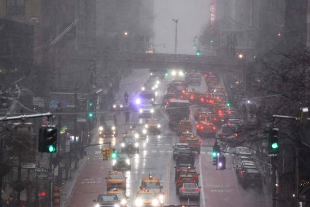 Pedestrians and cars move along 42nd Street in the Manhattan borough of New York City on February 22, 2026. A fast-developing storm is threatening to pummel the US East Coast with a foot (30cm) or more of snow beginning Sunday, bringing Mother Nature's wrath to a region that only just dug out from a previous winter wallop. Meteorologists issued blizzard warnings for New York and parts of at least six states, warning Saturday that heavy snow and gale-force winds are forecast to slam all major cities along the densely populated Interstate 95 northeast corridor, including Philadelphia, Boston and even Washington further south. (Photo by CHARLY TRIBALLEAU / AFP)
