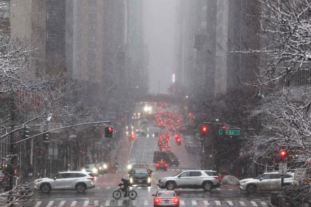 Pedestrians and cars move along 42nd Street in the Manhattan borough of New York City on February 22, 2026. A fast-developing storm is threatening to pummel the US East Coast with a foot (30cm) or more of snow beginning Sunday, bringing Mother Nature's wrath to a region that only just dug out from a previous winter wallop. Meteorologists issued blizzard warnings for New York and parts of at least six states, warning Saturday that heavy snow and gale-force winds are forecast to slam all major cities along the densely populated Interstate 95 northeast corridor, including Philadelphia, Boston and even Washington further south. (Photo by CHARLY TRIBALLEAU / AFP)
