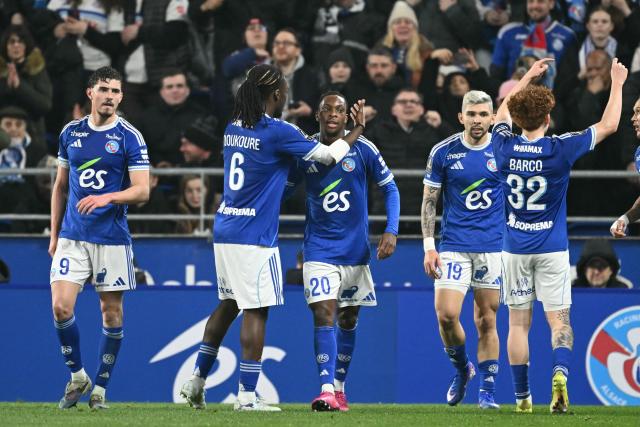 Strasbourg's Ivorian forward #20 Martial Godo (C) celebrates scoring his team's first goal during the French L1 football match between RC Strasbourg Alsace and Olympique Lyonnais (OL) at the Stade de la Meinau in Strasbourg on February 22, 2026. (Photo by SEBASTIEN BOZON / AFP)