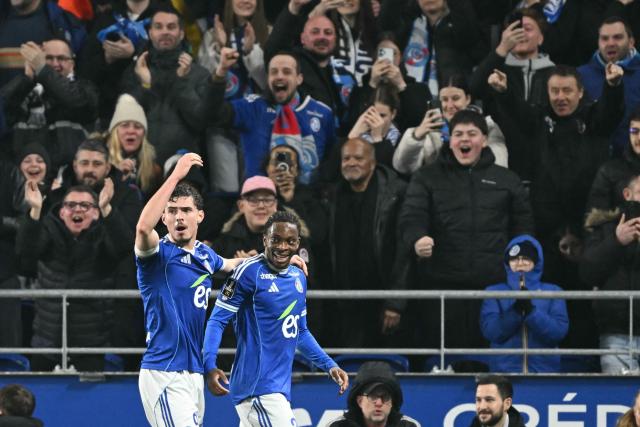 Strasbourg's Ivorian forward #20 Martial Godo (R) celebrates scoring his team's first goal during the French L1 football match between RC Strasbourg Alsace and Olympique Lyonnais (OL) at the Stade de la Meinau in Strasbourg on February 22, 2026. (Photo by SEBASTIEN BOZON / AFP)