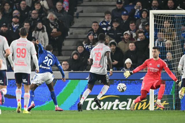Strasbourg's Ivorian forward #20 Martial Godo (L) scores his team's first goal during the French L1 football match between RC Strasbourg Alsace and Olympique Lyonnais (OL) at the Stade de la Meinau in Strasbourg on February 22, 2026. (Photo by SEBASTIEN BOZON / AFP)