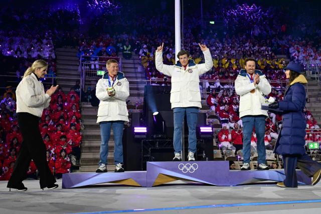 President of the International Olympic Committee (IOC) Kirsty Coventry (L) applauds as (From 2ndL) silver medallist Norway's Martin Loewstroem Nyenget, gold medallist Norway's Johannes Hoesflot Klaebo and bronze medallist Norway's Emil Iversen celebrate on the podium for the men's cross country 50km mass start final event of the Milano Cortina 2026 Winter Olympic Games, within the games' closing ceremony at the Verona Arena in Verona on February 22, 2026. (Photo by Stefano RELLANDINI / AFP)