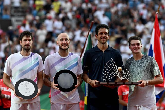 Brazil's couple Marcelo Melo (3-L) and Joao Fonseca (R) celebrates pose with the tropy  after winning their men's doubles final match against Netherlands's Robin Haase (L) and Germany's Constantin Frantzen at the Rio Open tennis tournament in Rio de Janeiro, Brazil, on February 22, 2026. (Photo by MAURO PIMENTEL / AFP)