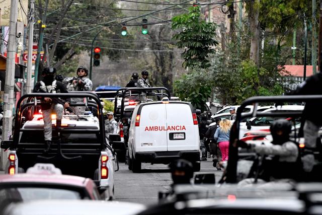 Mexican National Guard special forces escort an ambulance from the forensic service upon its arrival at the Specialized Prosecutor's Office for Organized Crime (FEMDO) headquarters in Mexico City on February 22, 2026. Mexico confirmed on February 22, 2026, that soldiers killed a powerful drug cartel leader who was one of the most wanted men here and in the United States. Nemesio Oseguera, the 59-year-old leader of the violent Jalisco New Generation Cartel, was wounded in a clash with soldiers in the town of Tapalpa and died while being flown to Mexico City, the army said in a statement. (Photo by Alfredo ESTRELLA / AFP)