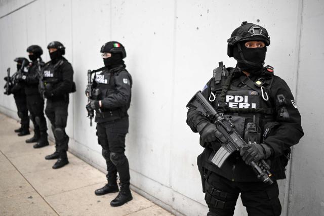 Members of the Special Reaction and Intervention Group (GERI) of the Investigative Police (PDI) stand guard around the Specialized Prosecutor's Office for Organized Crime (FEMDO) headquarters in Mexico City, on February 22, 2026. Mexico confirmed on February 22, 2026, that soldiers killed a powerful drug cartel leader who was one of the most wanted men here and in the United States. Nemesio Oseguera, the 59-year-old leader of the violent Jalisco New Generation Cartel, was wounded in a clash with soldiers in the town of Tapalpa and died while being flown to Mexico City, the army said in a statement. (Photo by Alfredo ESTRELLA / AFP)