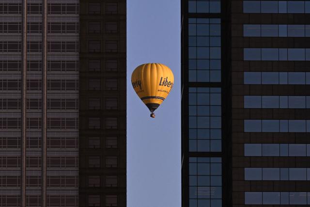 A hot-air balloon carrying tourists passes by the Melbourne central business district skyline during an early morning flight on February 23, 2026. (Photo by William WEST / AFP)