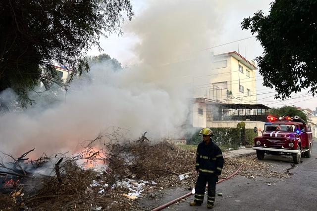 Firefighters work to put out a fire at an open-air garbage dumping site in a neighborhood of Havana, on February 22, 2026.  (Photo by Yamil LAGE / AFP)