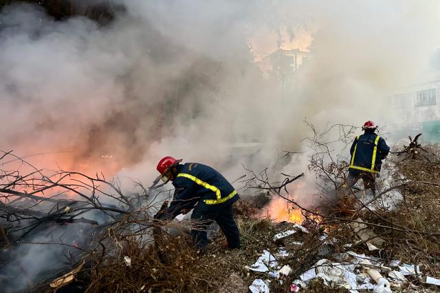 Firefighters work to put out a fire at an open-air garbage dumping site in a neighborhood of Havana, on February 22, 2026.  (Photo by Yamil LAGE / AFP)