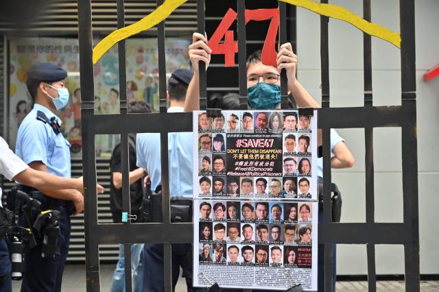 (FILES) A protester stands behind a mock jail with photos of the 47 pro-democracy figures already in prison as Hong Kong's political elite on September 19, 2021 began selecting a powerful commmittee which will choose the city's next leader and nearly half the city's legislature under a new "patriots only" system imposed by Beijing. Hong Kong's Court of Appeal upheld the jailing of 12 democracy campaigners on February 23, 2026 as part of a high-profile subversion case under a Beijing-imposed national security law. (Photo by Peter PARKS / AFP)