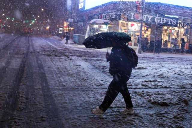 A man crosses Manhattan's 8th Avenue during a snowfall in New York City, on February 22, 2026. A fast-developing storm is threatening to pummel the US East Coast with a foot (30cm) or more of snow beginning Sunday, bringing Mother Nature's wrath to a region that only just dug out from a previous winter wallop. Meteorologists issued blizzard warnings for New York and parts of at least six states, warning Saturday that heavy snow and gale-force winds are forecast to slam all major cities along the densely populated Interstate 95 northeast corridor, including Philadelphia, Boston and even Washington further south. (Photo by CHARLY TRIBALLEAU / AFP)