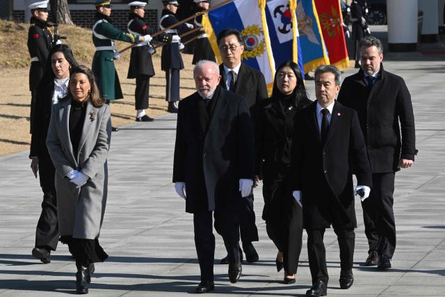Brazil's President Luiz Inacio Lula da Silva (C) and his wife Rosangela da Silva (L) visit the National Cemetery in Seoul on February 23, 2026, during his state visit to South Korea. (Photo by Jung Yeon-je / AFP)