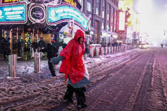 A woman walks along Manhattan's Times Square during a snowfall in New York City, on February 22, 2026. A fast-developing storm is threatening to pummel the US East Coast with a foot (30cm) or more of snow beginning Sunday, bringing Mother Nature's wrath to a region that only just dug out from a previous winter wallop. Meteorologists issued blizzard warnings for New York and parts of at least six states, warning Saturday that heavy snow and gale-force winds are forecast to slam all major cities along the densely populated Interstate 95 northeast corridor, including Philadelphia, Boston and even Washington further south. (Photo by CHARLY TRIBALLEAU / AFP)