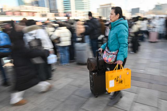 People arrive at Beijing Railway Station on February 23, 2026, the final day of the Spring Festival holiday marking the Lunar New Year of the Horse. (Photo by Pedro PARDO / AFP)