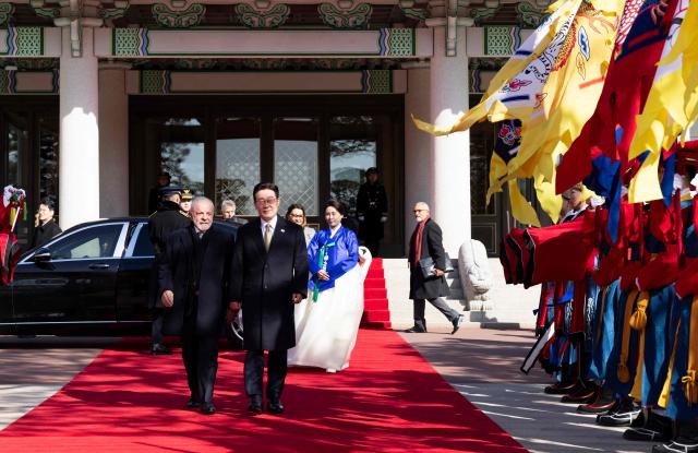 Brazil's President Luiz Inacio Lula da Silva (L) and  South Korea's President Lee Jae Myung (R) inspect an honour guard during a welcome ceremony at the presidential Blue House in Seoul on February 23, 2026. Brazilians could more easily get their hands on coveted "K-beauty" products under a deal struck on February 23 during President Luiz Inacio Lula da Silva's state visit to South Korea. Lula and South Korean leader Lee Jae Myung signed a slew of agreements with the Brazilian president in Seoul, covering everything from agriculture to business cooperation. (Photo by JEON HEON-KYUN / POOL / AFP)