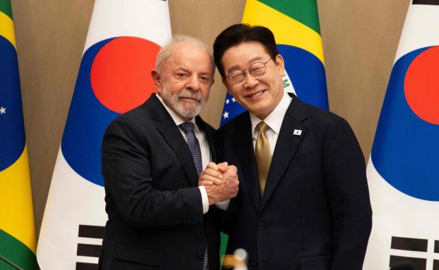 TOPSHOT - Brazil's President Luiz Inacio Lula da Silva (L) and South Korea's President Lee Jae Myung (R) shake hands prior to their meeting at the presidential Blue House in Seoul on February 23, 2026. Brazilians could more easily get their hands on coveted "K-beauty" products under a deal struck on February 23 during President Luiz Inacio Lula da Silva's state visit to South Korea. Lula and South Korean leader Lee Jae Myung signed a slew of agreements with the Brazilian president in Seoul, covering everything from agriculture to business cooperation. (Photo by JEON HEON-KYUN / POOL / AFP)