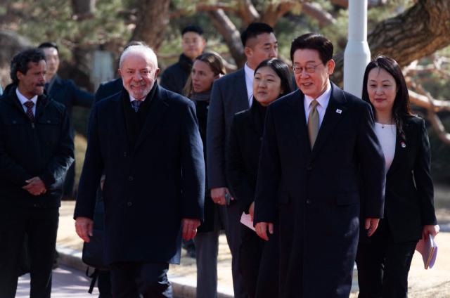 Brazil's President Luiz Inacio Lula da Silva (L) and South Korea's President Lee Jae Myung (R) walk during a welcome ceremony at the presidential Blue House in Seoul on February 23, 2026. Brazilians could more easily get their hands on coveted "K-beauty" products under a deal struck on February 23 during President Luiz Inacio Lula da Silva's state visit to South Korea. Lula and South Korean leader Lee Jae Myung signed a slew of agreements with the Brazilian president in Seoul, covering everything from agriculture to business cooperation. (Photo by JEON HEON-KYUN / POOL / AFP)
