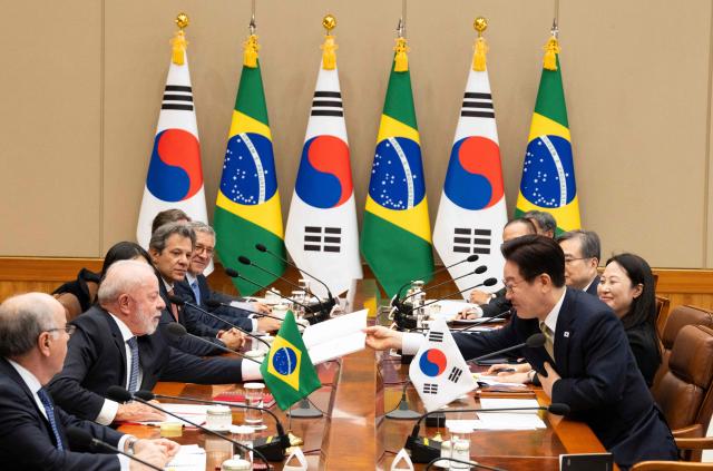 Brazil's President Luiz Inacio Lula da Silva (2nd L) talks with South Korea's President Lee Jae Myung (R) during their meeting at the presidential Blue House in Seoul on February 23, 2026. Brazilians could more easily get their hands on coveted "K-beauty" products under a deal struck on February 23 during President Luiz Inacio Lula da Silva's state visit to South Korea. Lula and South Korean leader Lee Jae Myung signed a slew of agreements with the Brazilian president in Seoul, covering everything from agriculture to business cooperation. (Photo by JEON HEON-KYUN / POOL / AFP)