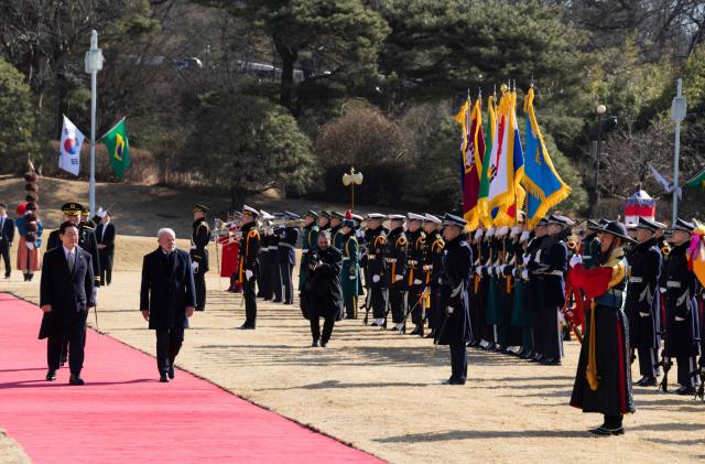 Brazil's President Luiz Inacio Lula da Silva (2nd L) and South Korea's President Lee Jae Myung (L) inspect an honour guard during a welcome ceremony at the presidential Blue House in Seoul on February 23, 2026. Brazilians could more easily get their hands on coveted "K-beauty" products under a deal struck on February 23 during President Luiz Inacio Lula da Silva's state visit to South Korea. Lula and South Korean leader Lee Jae Myung signed a slew of agreements with the Brazilian president in Seoul, covering everything from agriculture to business cooperation. (Photo by JEON HEON-KYUN / POOL / AFP)
