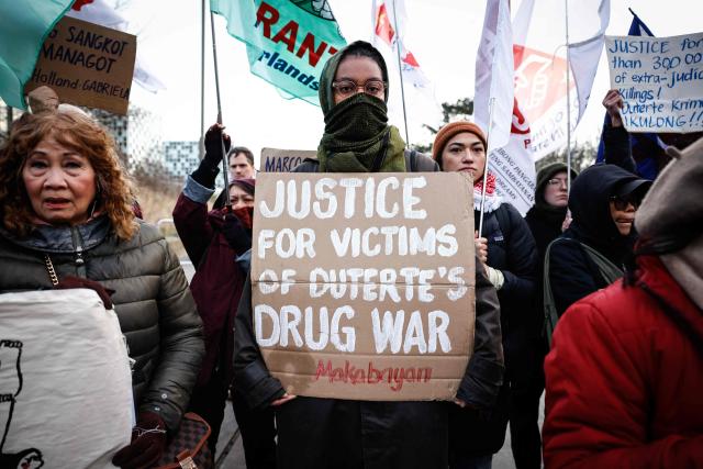 Protestors, rallying in support of the detention of former Philippine's president Rodrigo Duterte, hold a placard which reads as  «Justice for victims of Dutertets drug waR» outside of the International Criminal Court (ICC) where he will be questioned by the International Criminal Court on charges of crimes against humanity, in The Hague on February 23, 2026. As the 80-year-old will not be present at the hearing in The Hague after the court granted a defence request to waive his right to appear, despite judges ruling that he was fit to take part, the "confirmation of charges" hearing, taking place over four days, will determine whether there is enough evidence against Duterte to proceed to a trial. (Photo by Simon Wohlfahrt / AFP)