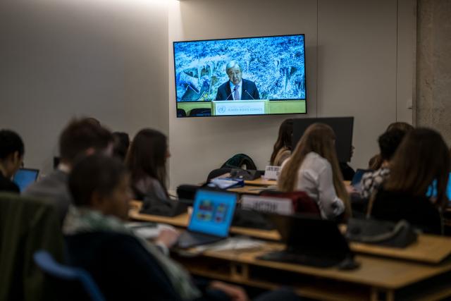 UN Secretary-General Antonio Guterres appears on a TV screen as he delivers a speech at the opening of the 61st session of the UN Human Rights Council at the United Nations office in Geneva on February 23, 2026. Human rights are under "full-scale attack around the world", United Nations chief Antonio Guterres warned on February 23, 2026, with the most powerful often leading the charge. (Photo by Fabrice COFFRINI / AFP)