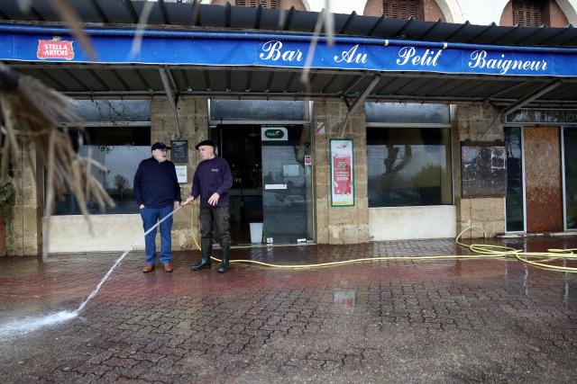 A person cleans mud from the pavement outside a bar as the Garonne river water have receded following days of flooding in La Reole, east of Bordeaux, on February 23, 2026. (Photo by ROMAIN PERROCHEAU / AFP)