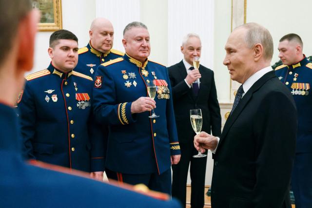 In this pool photograph distributed by the Russian state agency Sputnik, Russia's President Vladimir Putin (2nd-R) makes a toast with servicemen awarded with Gold Star medals of 'Hero of Russia' during a ceremony on Defender of the Fatherland Day in Moscow on February 23, 2026. (Photo by Mikhail METZEL / POOL / AFP)