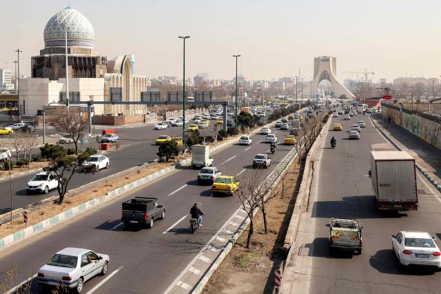 Vehicles move along a highway near Tehran's landmark Azadi (Freedom) Tower in Tehran on February 23, 2026. Azadi Tower, formerly known as Shahyad Tower (Shah's Memorial Tower'), was commissioned by Mohammad Reza Pahlavi, the last Shah of Iran, to mark the 2,500-year celebration of the Persian Empire, and was completed in 1971. It was erected at the westernmost entrance to the city of Tehran. (Photo by ATTA KENARE / AFP)