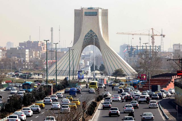 TOPSHOT - Vehicles move along a highway near Tehran's landmark Azadi (Freedom) Tower in Tehran on February 23, 2026. The 45-metre-tall marble-clad Azadi Tower, formerly known as Shahyad Tower (Shah's Memorial Tower'), was commissioned by Mohammad Reza Pahlavi, the last Shah of Iran, to mark the 2,500-year celebration of the Persian Empire, and completed in 1971. It was erected at the westernmost entrance to the city of Tehran. (Photo by ATTA KENARE / AFP)