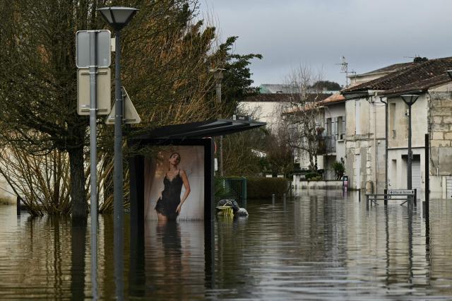 This photograph shows an advert at a bus stop on a flooded street following severe flooding from storm Nils in Saintes, south-western France, on February 23, 2026. (Photo by Philippe LOPEZ / AFP)