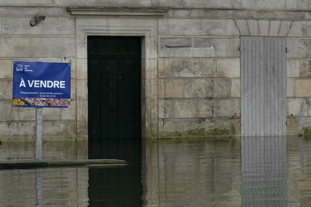 A sign reading "For sale" stands in front of a house on a flooded street following severe flooding from storm Nils in Saintes, south-western France, on February 23, 2026. (Photo by Philippe LOPEZ / AFP)