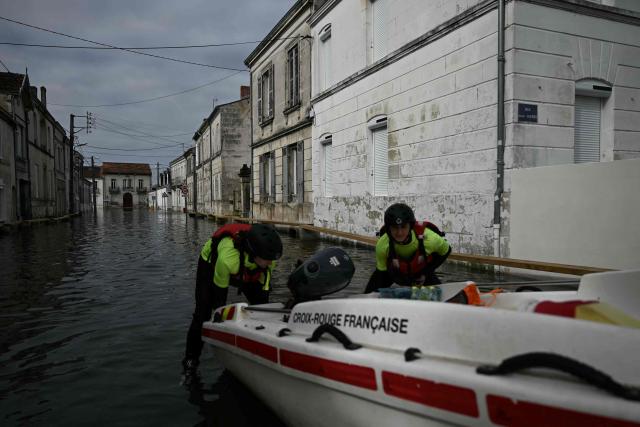 Members of the Red Cross push their boat on a flooded street as they provide assistance to residents following severe flooding from storm Nils in Saintes, south-western France, on February 23, 2026. (Photo by Philippe LOPEZ / AFP)