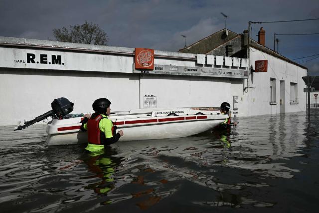 Members of the Red Cross push their boat in the water on a flooded street as they provide assistance to residents following severe flooding from storm Nils in Saintes, south-western France, on February 23, 2026. (Photo by Philippe LOPEZ / AFP)