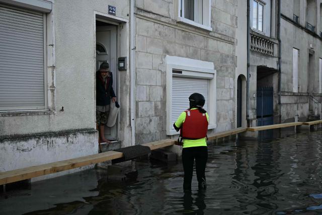A member of the Red Cross talks with a resident on a flooded street as they provide assistance following severe flooding from storm Nils in Saintes, south-western France, on February 23, 2026. (Photo by Philippe LOPEZ / AFP)