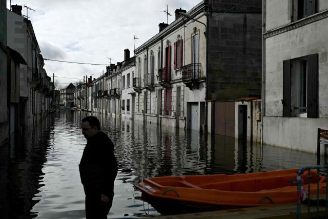 A resident stands by a boat on a flooded street following severe flooding from storm Nils in Saintes, south-western France, on February 23, 2026. (Photo by Philippe LOPEZ / AFP)