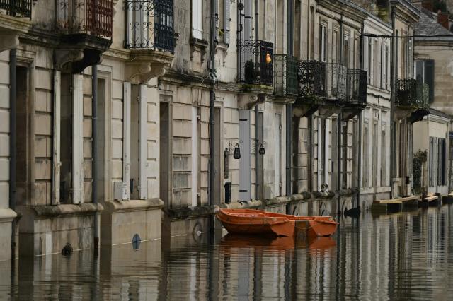 A boat used by resident floats in front of houses on a flooded street following severe flooding from storm Nils in Saintes, south-western France, on February 23, 2026. (Photo by Philippe LOPEZ / AFP)