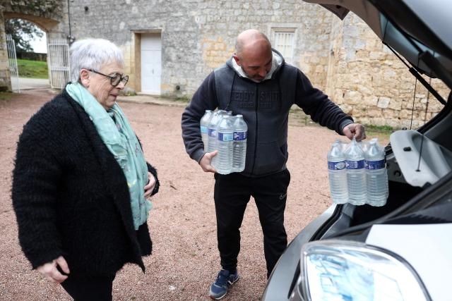 Local residents receive bottled water after tap water becomes undrinkable following days of severe flooding in Sainte-Croix-du-Mont, southwestern France, on February 23, 2026. (Photo by ROMAIN PERROCHEAU / AFP)