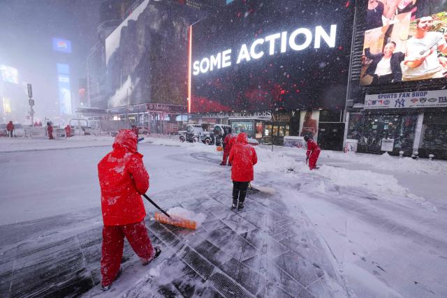 Workers clear the snow covered street in Times Square during a winter storm in the Manhattan borough of New York City on February 23, 2026. New York ordered drivers off the road and shut down schools on Monday, while residents hunkered down for a massive snowstorm hitting the United States northeast. The National Weather Service (NWS) said in a post on X that "heavy snow is still falling" at 5:28 am local time (1028 GMT) on Monday adding that a the total snowfall stands at 14.9 inches. (Photo by TIMOTHY A.CLARY / AFP)