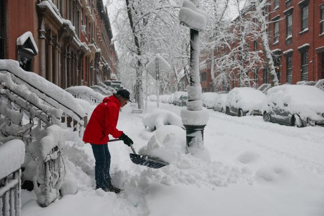 A person clears snow from the sidewalk during a winter storm in the Brooklyn borough of New York City on February 23, 2026. New York ordered drivers off the road and shut down schools on Monday, while residents hunkered down for a massive snowstorm hitting the United States northeast. The National Weather Service (NWS) said in a post on X that "heavy snow is still falling" at 5:28 am local time (1028 GMT) on Monday adding that a the total snowfall stands at 14.9 inches. (Photo by ANGELA WEISS / AFP)