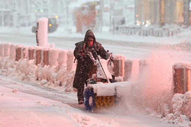 A person uses a snow blower to clear a sidewalk during a winter storm in the Manhattan borough of New York City on February 23, 2026. New York ordered drivers off the road and shut down schools on Monday, while residents hunkered down for a massive snowstorm hitting the United States northeast. The National Weather Service (NWS) said in a post on X that "heavy snow is still falling" at 5:28 am local time (1028 GMT) on Monday adding that a the total snowfall stands at 14.9 inches. (Photo by TIMOTHY A. CLARY / AFP)