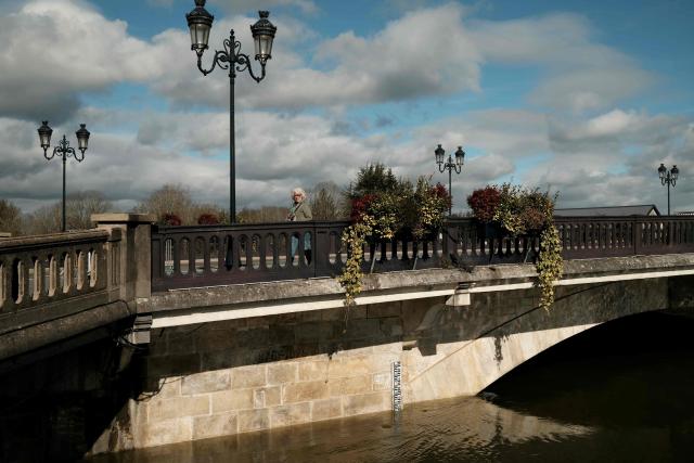 A woman crosses a bridge over the flooded banks of the Charente River following severe flooding caused by Storm Nils in Saintes, south-western France, on February 23, 2026. (Photo by Philippe LOPEZ / AFP)