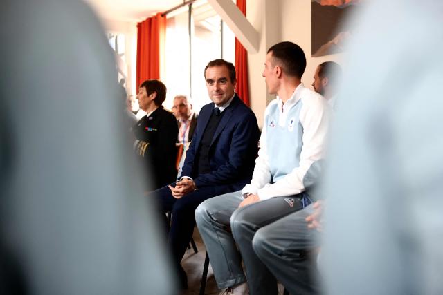 France's Prime Minister Sebastien Lecornu sits next to France's Quentin Fillon Maillet during a ceremony of arrival of the Olympic flag marking the handover from Milano Cortina 2026 to French Alps 2030 Winter Olympic Games, in the French Alps in Albertville, south-eastern France on February 23, 2026. (Photo by Alex MARTIN / AFP)