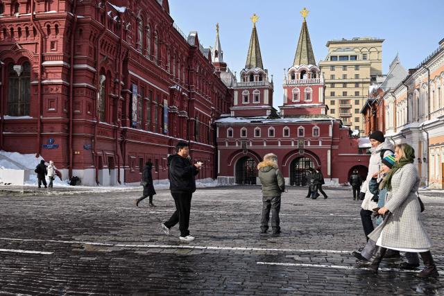People walk near the State Historical Museum in central Moscow, during the Defender of the Fatherland Day on February 23, 2026. (Photo by Hector RETAMAL / AFP)